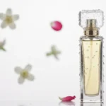 Butelka perfum na białym tle z kroplami wody i kwiatami w tle, symbolizujące trwałość i zapach